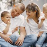 Family with cute little children. Father in a white shirt. People have a picnic on a yard.