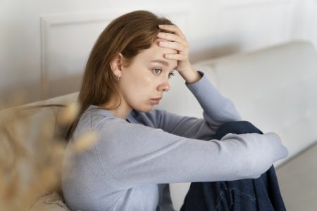 anxious-woman-sitting-couch-side-view